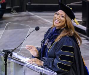 Graduation speaker delivering speech at academic ceremony in cap and gown.