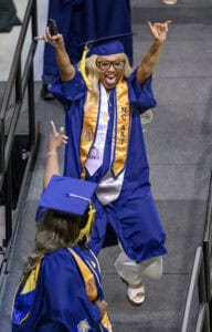 Graduation celebration with smiling graduate in blue cap and gown at CAES News event.