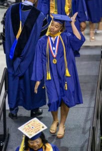 Graduation cap and gown ceremony with smiling graduate celebrating achievement.