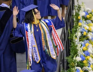Graduation graduate celebrating in cap and gown at commencement ceremony.
