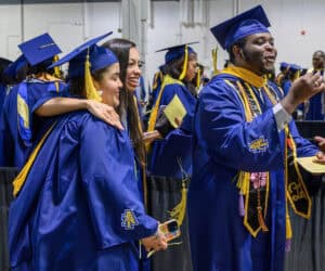 Graduates in blue caps and gowns celebrating at a graduation ceremony, showcasing academic achieveme.