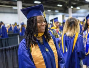 Graduation cap and gown ceremony with smiling graduate at a university event.