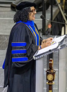 Graduation speaker delivering speech at commencement ceremony in academic regalia.