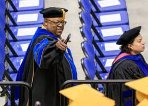 Graduation ceremony with graduates in academic regalia at an indoor venue.