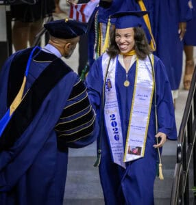 Graduation ceremony with smiling graduate in blue cap and gown, celebrating academic achievement and.