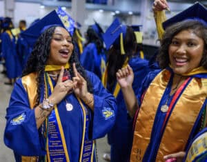 Graduates celebrating at a graduation ceremony in caps and gowns.