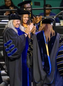 Graduation ceremony with smiling graduates in academic regalia celebrating achievement.