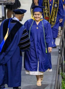 Graduation ceremony with smiling female graduate in blue cap and gown at CAES News event.