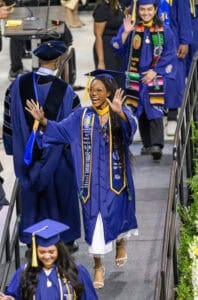 Graduation ceremony with students in blue caps and gowns celebrating academic achievement.