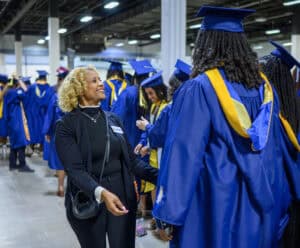 Graduation ceremony with students in blue caps and gowns celebrating academic achievement.