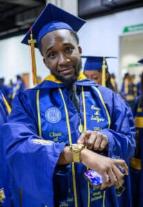 Graduation student in cap and gown checking watch at ceremony.