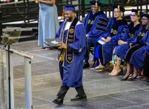 Graduation ceremony with students in academic regalia at CAES News event.