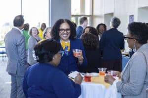 Networking event with diverse professionals engaging and enjoying drinks at a modern conference.