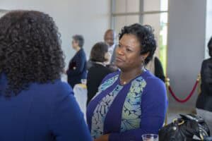 Engaged woman at professional networking event, discussing with a colleague indoors.