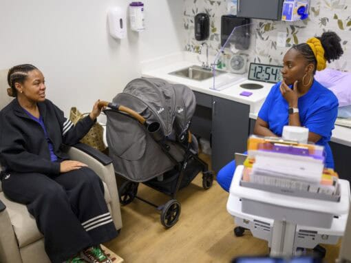 Doctor consulting with a patient in a medical office with a stroller nearby.