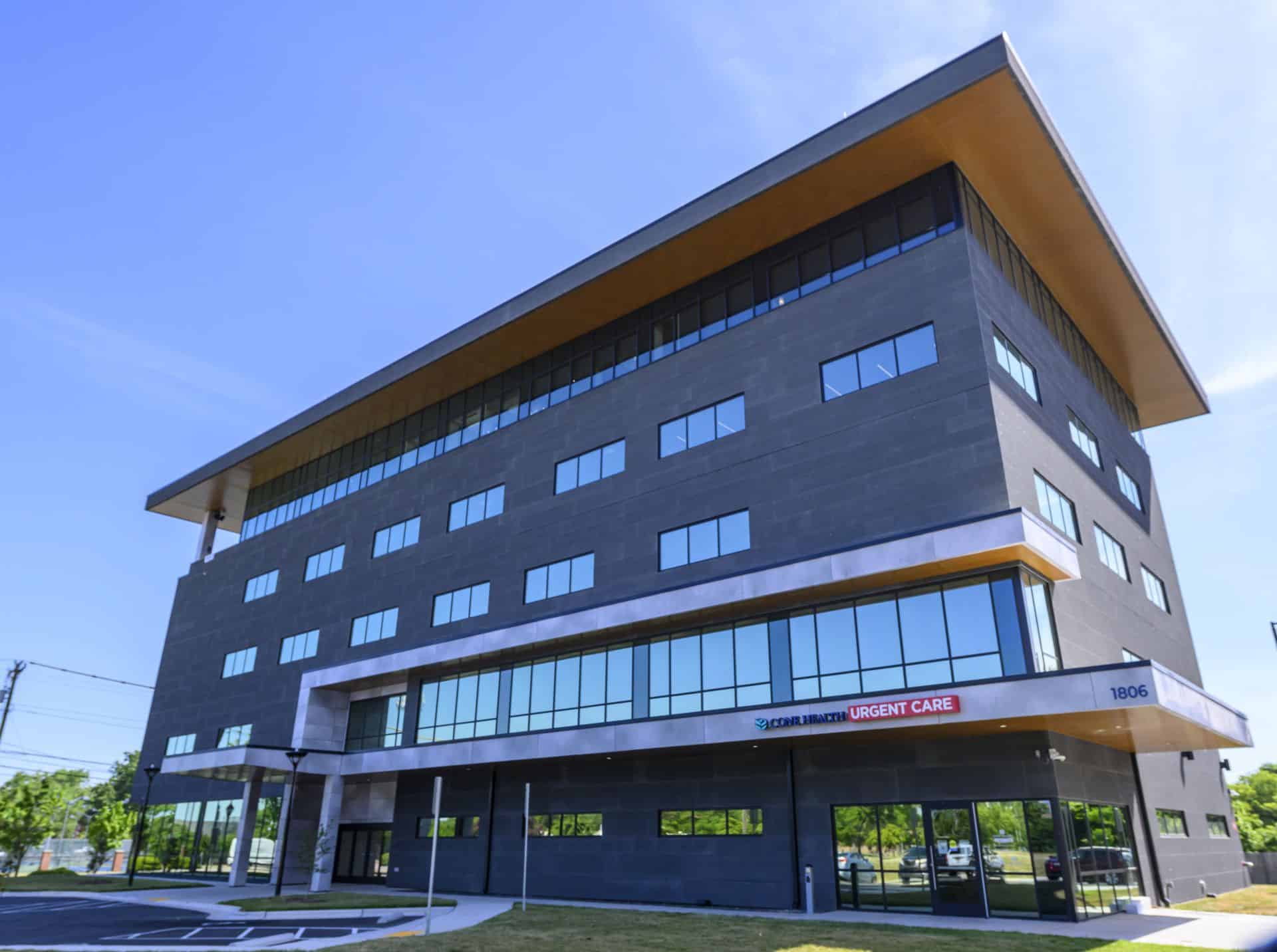 Modern hospital building with urgent care sign and large glass windows.